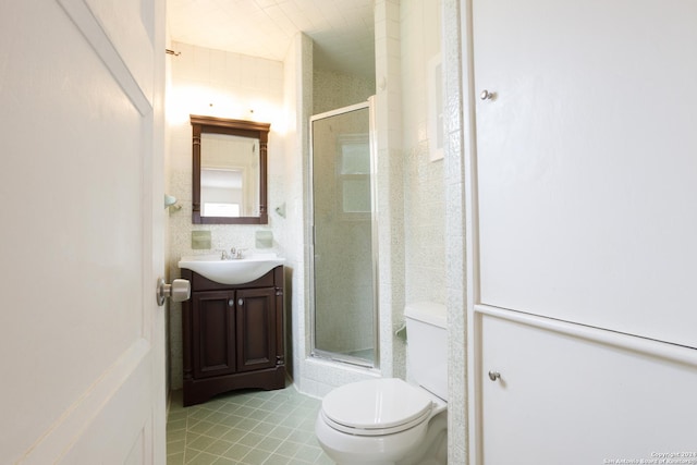 bathroom featuring a shower with door, vanity, tile patterned floors, and toilet