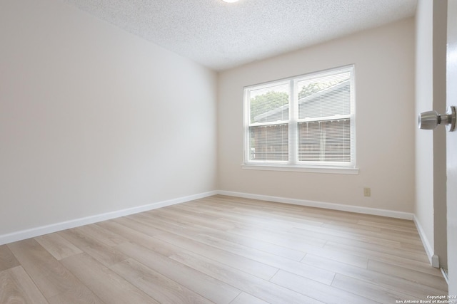 empty room featuring a textured ceiling and light hardwood / wood-style floors