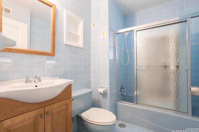 full bathroom featuring toilet, tile walls, vanity, enclosed tub / shower combo, and decorative backsplash