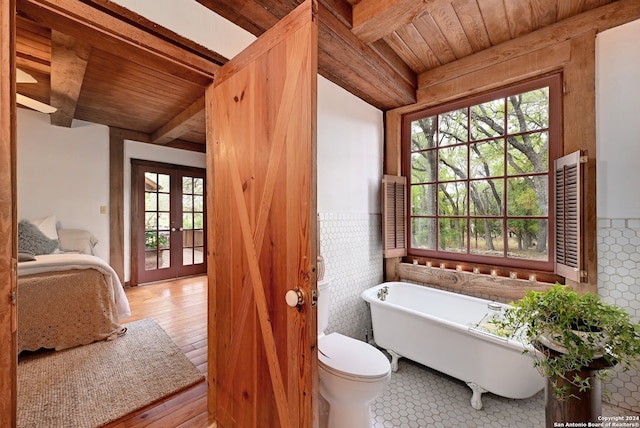 bathroom featuring hardwood / wood-style floors, a bathtub, wooden ceiling, french doors, and toilet