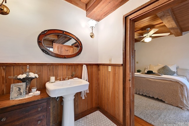 bathroom with ceiling fan, wood ceiling, beamed ceiling, and wood walls