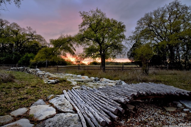 yard at dusk featuring a rural view