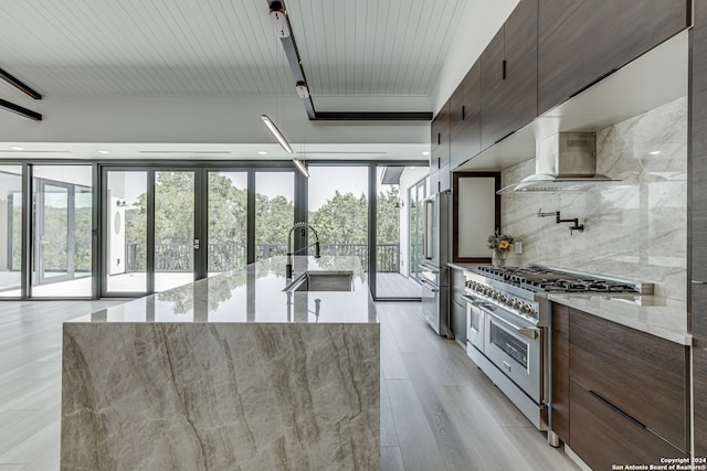 kitchen with decorative backsplash, sink, exhaust hood, light stone countertops, and stove