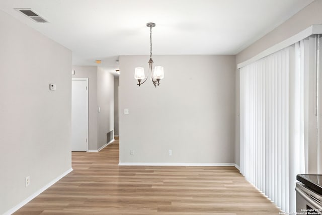 unfurnished dining area featuring an inviting chandelier and light hardwood / wood-style floors