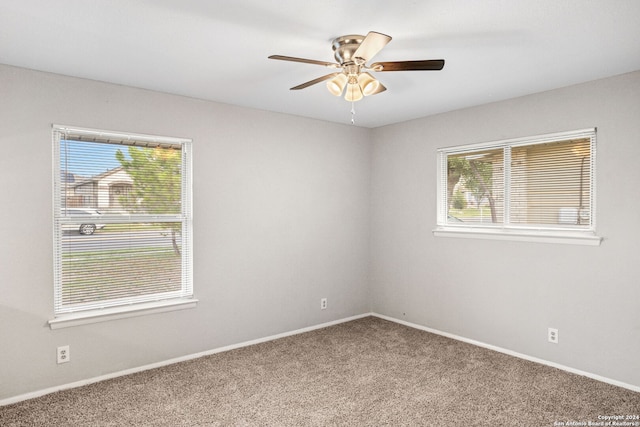 carpeted empty room with ceiling fan and a wealth of natural light