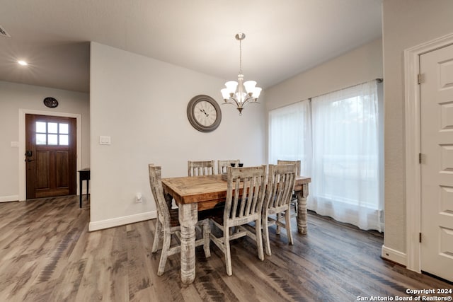 dining space with hardwood / wood-style floors and an inviting chandelier