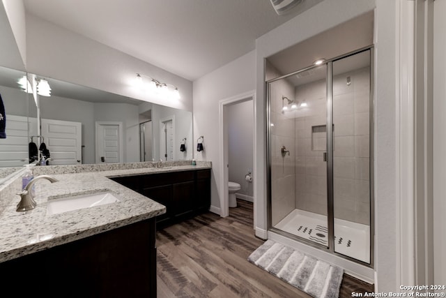 bathroom with walk in shower, double vanity, hardwood / wood-style floors, and toilet