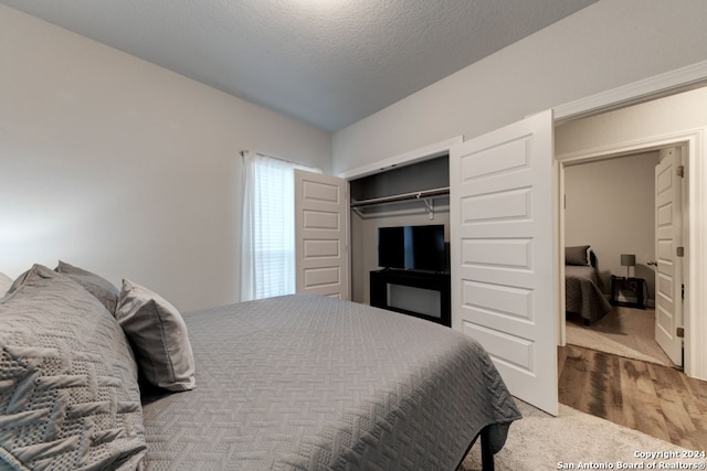 bedroom with a textured ceiling, a closet, and wood-type flooring