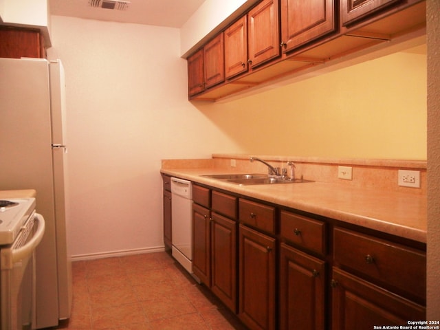 kitchen featuring light tile patterned floors, white appliances, and sink