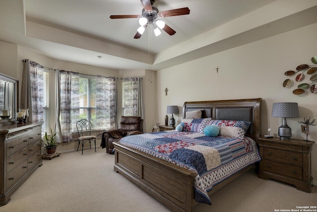 carpeted bedroom featuring ceiling fan and a tray ceiling