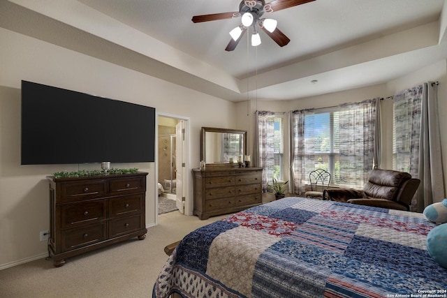 bedroom featuring ceiling fan, ensuite bath, a raised ceiling, and light carpet