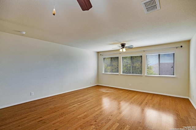 unfurnished room with a textured ceiling, light hardwood / wood-style floors, and ceiling fan