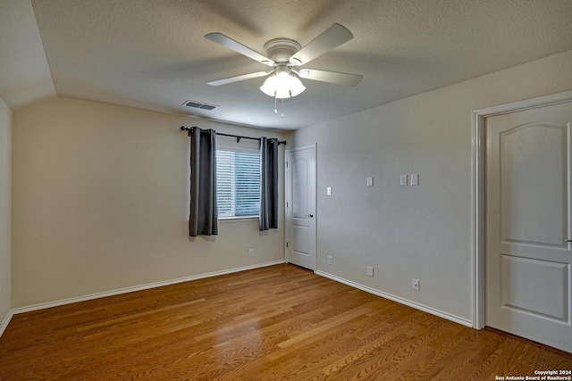 spare room with lofted ceiling, ceiling fan, a textured ceiling, and light wood-type flooring