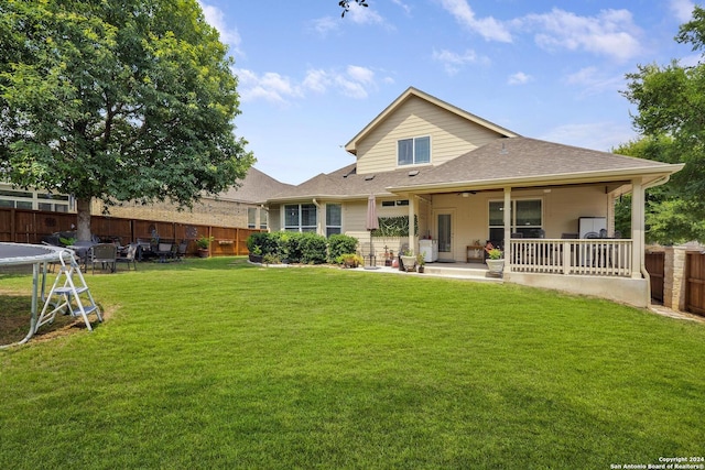 back of house featuring a yard and a trampoline