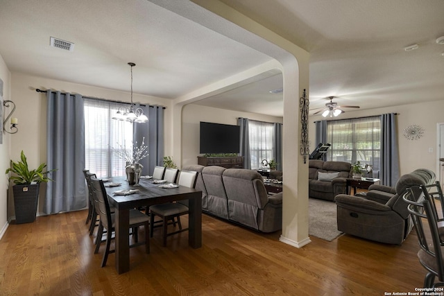 dining area featuring hardwood / wood-style flooring, a wealth of natural light, and ceiling fan with notable chandelier