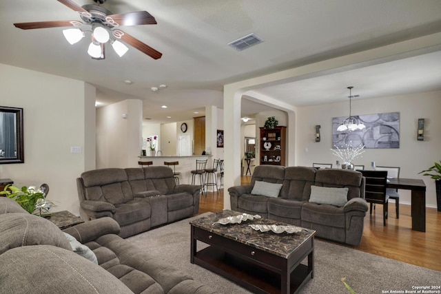 living room featuring ceiling fan with notable chandelier and hardwood / wood-style floors