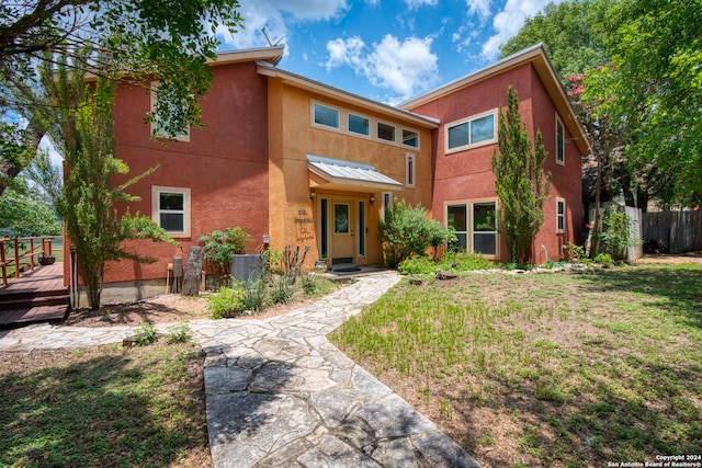 view of front of house featuring a deck, central AC unit, and a front yard