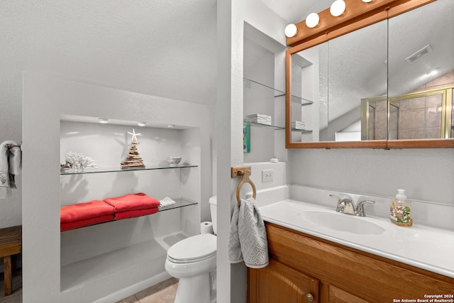 bathroom with vaulted ceiling, vanity, a textured ceiling, and toilet