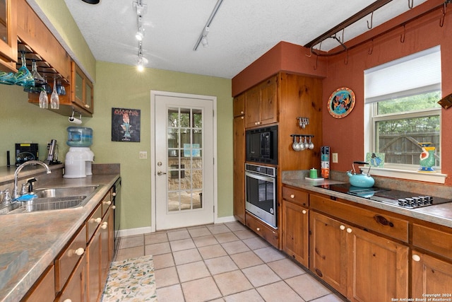 696 Faurie Rd, Lakehills, TX 78063 - kitchen with black appliances, a sink, brown cabinets, light tile patterned floors, and rail lighting