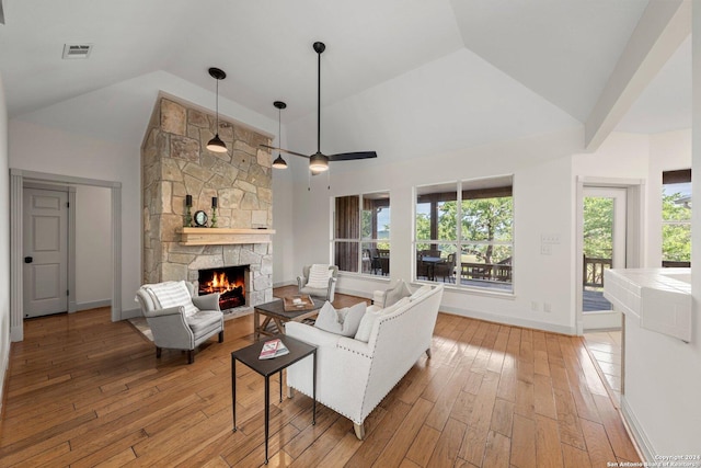 living room with high vaulted ceiling, a fireplace, and light hardwood / wood-style floors