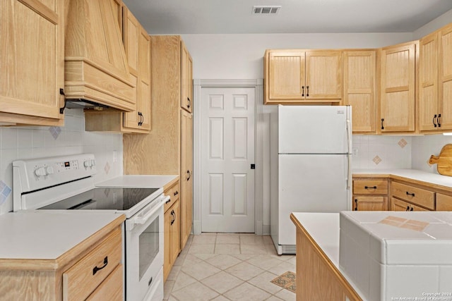 kitchen featuring premium range hood, light brown cabinets, backsplash, and white appliances