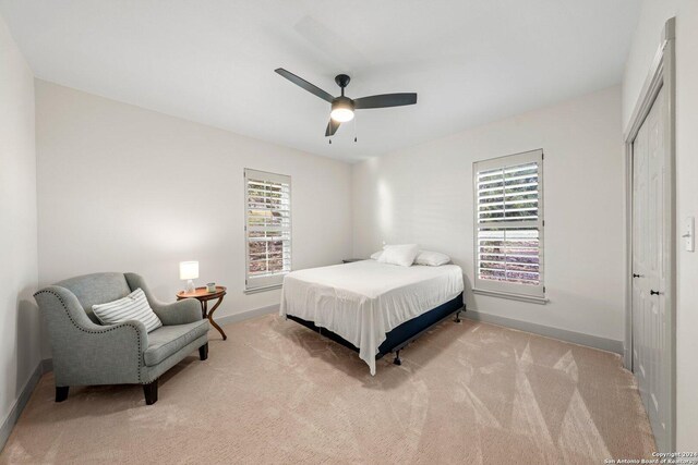 bedroom featuring light carpet, multiple windows, a closet, and ceiling fan