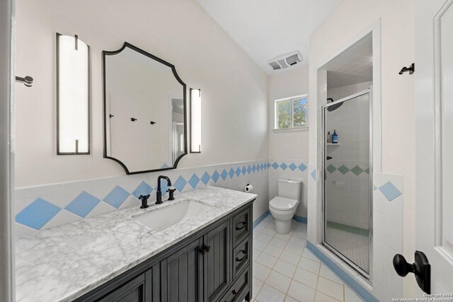 bathroom with vanity, walk in shower, tile walls, toilet, and tile patterned flooring