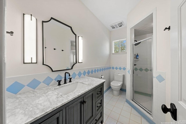 bathroom with a shower with door, vanity, tile patterned floors, and toilet