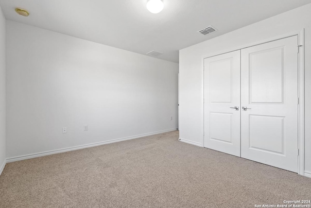 unfurnished bedroom with light colored carpet and a closet