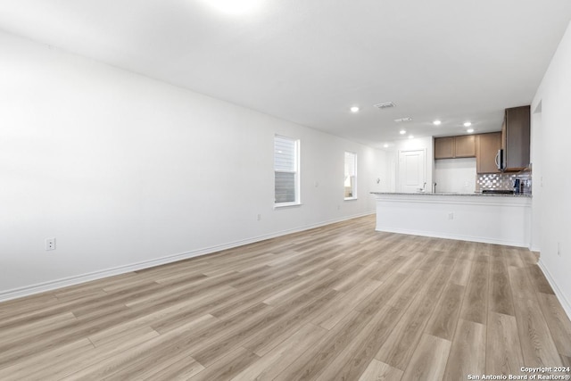 unfurnished living room featuring sink and light hardwood / wood-style floors