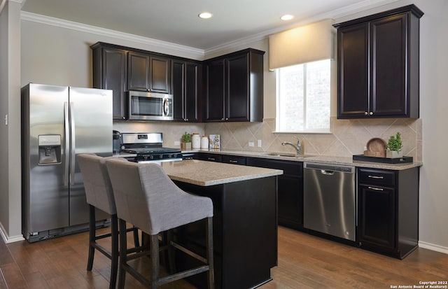 kitchen with a kitchen island, sink, dark hardwood / wood-style flooring, ornamental molding, and stainless steel appliances