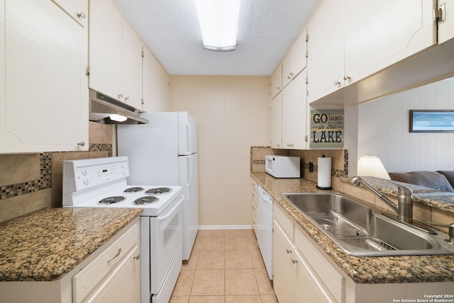 kitchen featuring white appliances, light tile patterned flooring, under cabinet range hood, decorative backsplash, and a sink