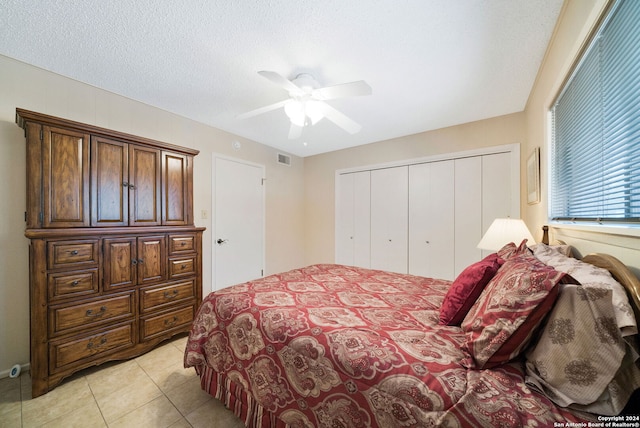 bedroom with light tile patterned floors, ceiling fan, a textured ceiling, a closet, and visible vents