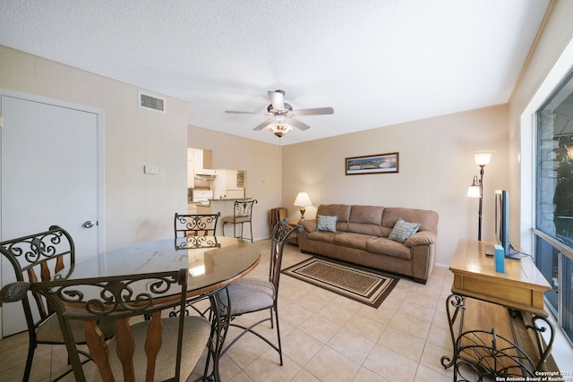 living room featuring a textured ceiling, ceiling fan, visible vents, and light tile patterned floors