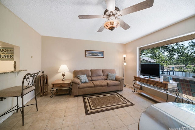 living area with light tile patterned floors, a ceiling fan, and a textured ceiling