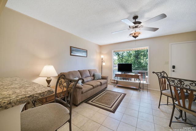 living area featuring a textured ceiling, a ceiling fan, and light tile patterned flooring