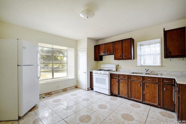 kitchen featuring plenty of natural light, white appliances, light countertops, and a sink