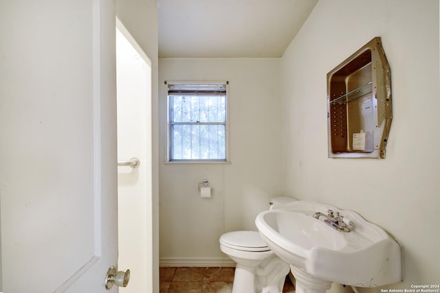 bathroom featuring tile patterned flooring, toilet, baseboards, and a sink