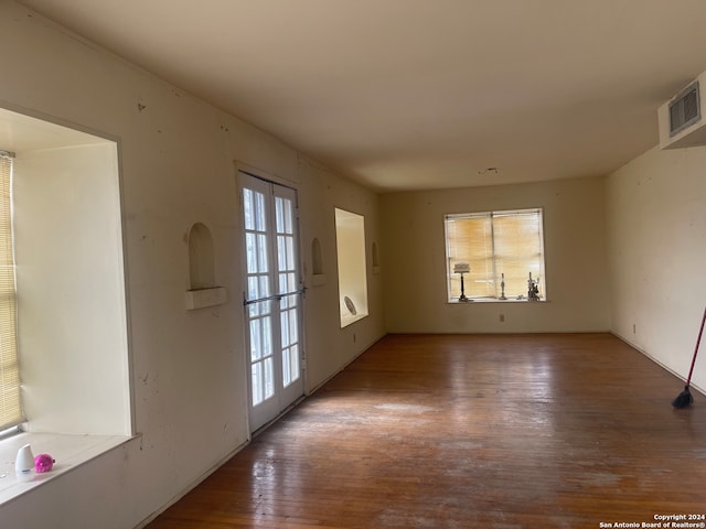 empty room with wood-type flooring, french doors, and a wealth of natural light