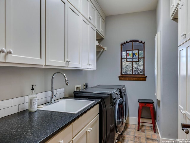 laundry room featuring cabinet space, baseboards, brick floor, washing machine and dryer, and a sink