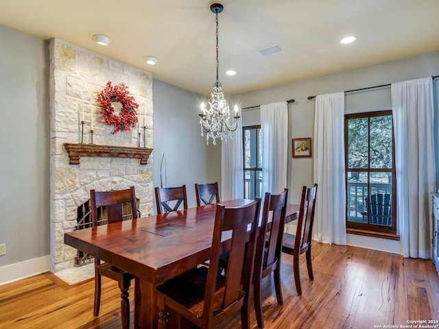 dining area with baseboards, visible vents, wood finished floors, a fireplace, and a notable chandelier