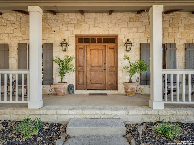 property entrance featuring stone siding and covered porch