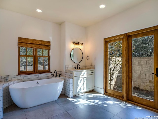 full bathroom featuring recessed lighting, a soaking tub, plenty of natural light, and vanity