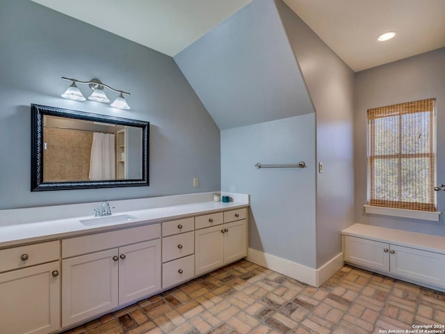 bathroom with brick floor, lofted ceiling, recessed lighting, vanity, and baseboards