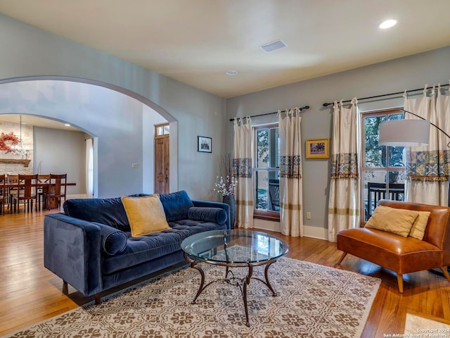 living room featuring arched walkways, light wood finished floors, recessed lighting, visible vents, and baseboards