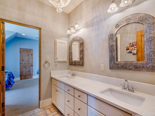 ensuite bathroom featuring a notable chandelier, double vanity, a sink, and baseboards