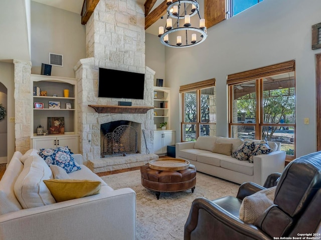 living area with a stone fireplace, plenty of natural light, visible vents, and a notable chandelier