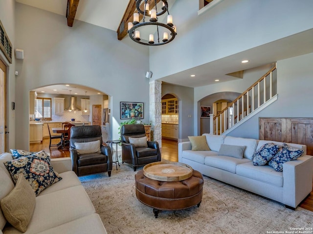 living room with arched walkways, light wood finished floors, beamed ceiling, and a chandelier