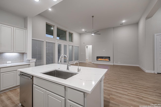 kitchen with sink, white cabinets, dishwasher, and a center island with sink