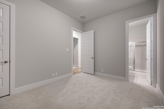 unfurnished bedroom with baseboards, visible vents, a textured ceiling, carpet flooring, and connected bathroom